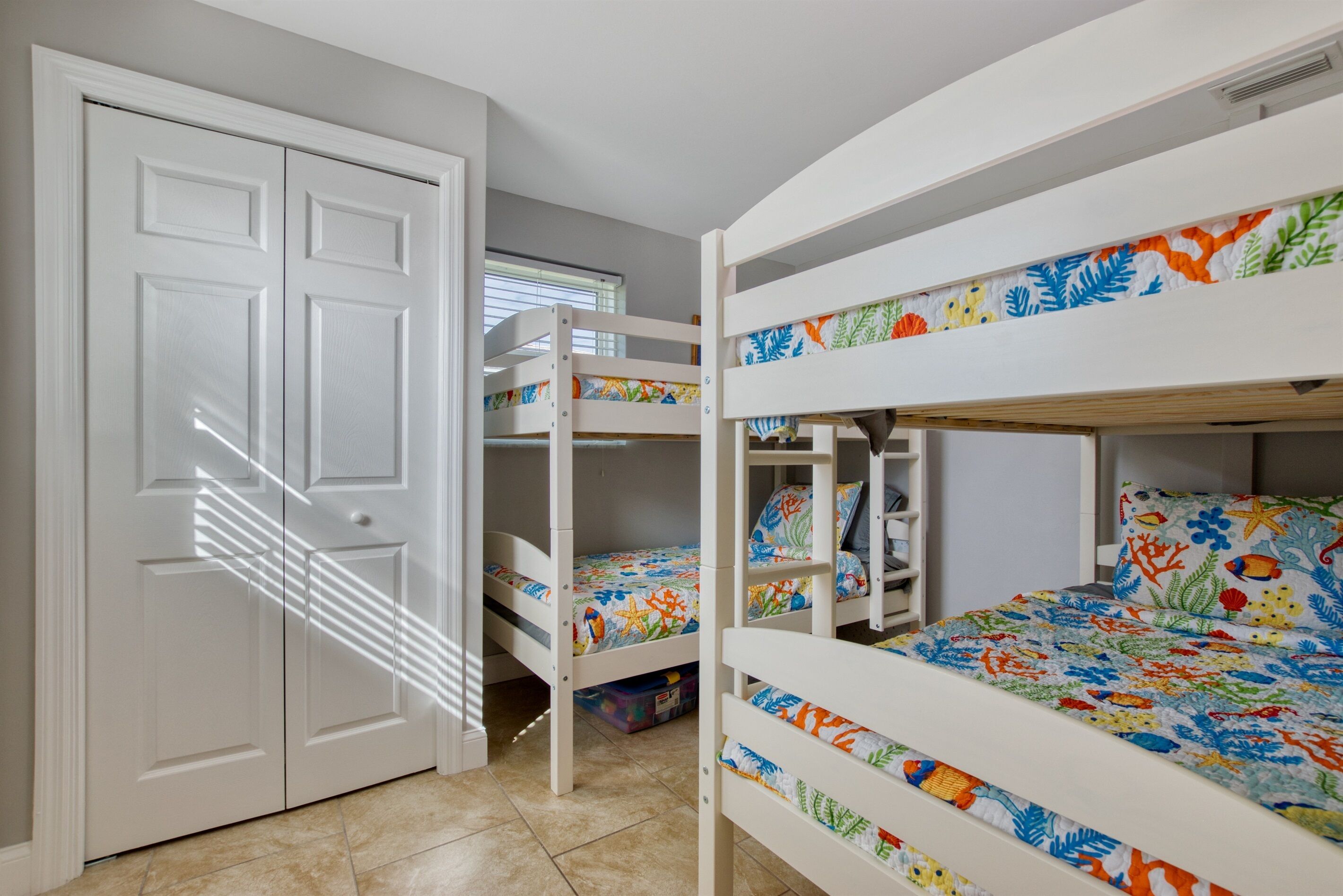 Quarto com beliche, porta branca e janela.