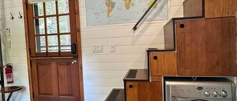 A wooden staircase with a washing machine, a world map, and a door with a window.