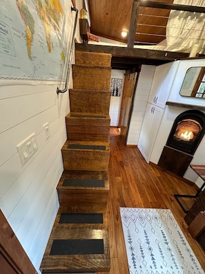 A wooden staircase leading to a loft bedroom with a fireplace. - New Listing! AmongstTheAspens - Off-Grid Tiny Home (Saco)