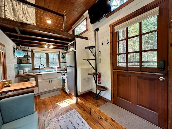 A compact kitchen with a wooden ceiling, a built-in stove, and a large window.