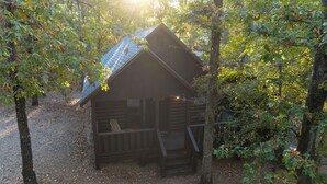 A small cabin with a sloped roof, surrounded by trees and a gravel path. - Jax Ridge-Studio 1 Bedroom (Broken Bow)