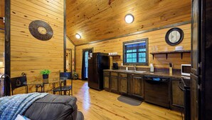 A compact kitchen with wooden walls, a refrigerator, microwave, and a sink. - Jax Ridge-Studio 1 Bedroom (Broken Bow)