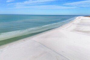 A wide sandy beach with gentle waves and a clear sky.