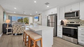 Una cocina moderna con armarios blancos, electrodomésticos de acero inoxidable y una isla central con taburetes.