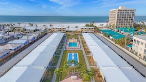Un hotel costero con varias edificaciones, una piscina central y vistas a la playa.