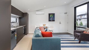 Un apartamento moderno con kitchenette, comedor y sala de estar con sofá y sillón.