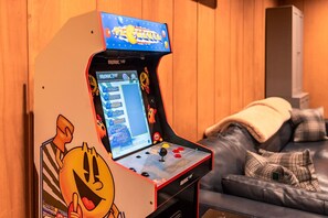A retro arcade machine with a screen displaying a game, placed in a room with wooden walls and a leather couch.