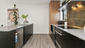 Een moderne keuken met donkere kastjes, een roestvrijstalen spoelbak en een ingebouwde oven.