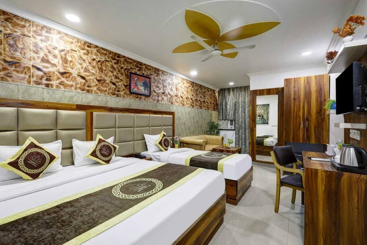 A hotel room with two beds, a sofa, a desk, and a television.