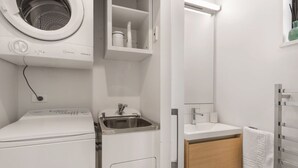 A compact laundry room with a washing machine, a sink, and a small cabinet.