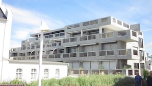 A multi-story building with a modern architectural design, featuring balconies and large windows. - Vacation apartment Bude 16 (Norderney)