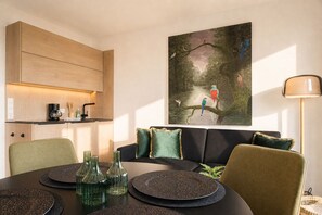 Un espace repas moderne avec un meuble en bois, un tableau représentant des oiseaux et une lampe.