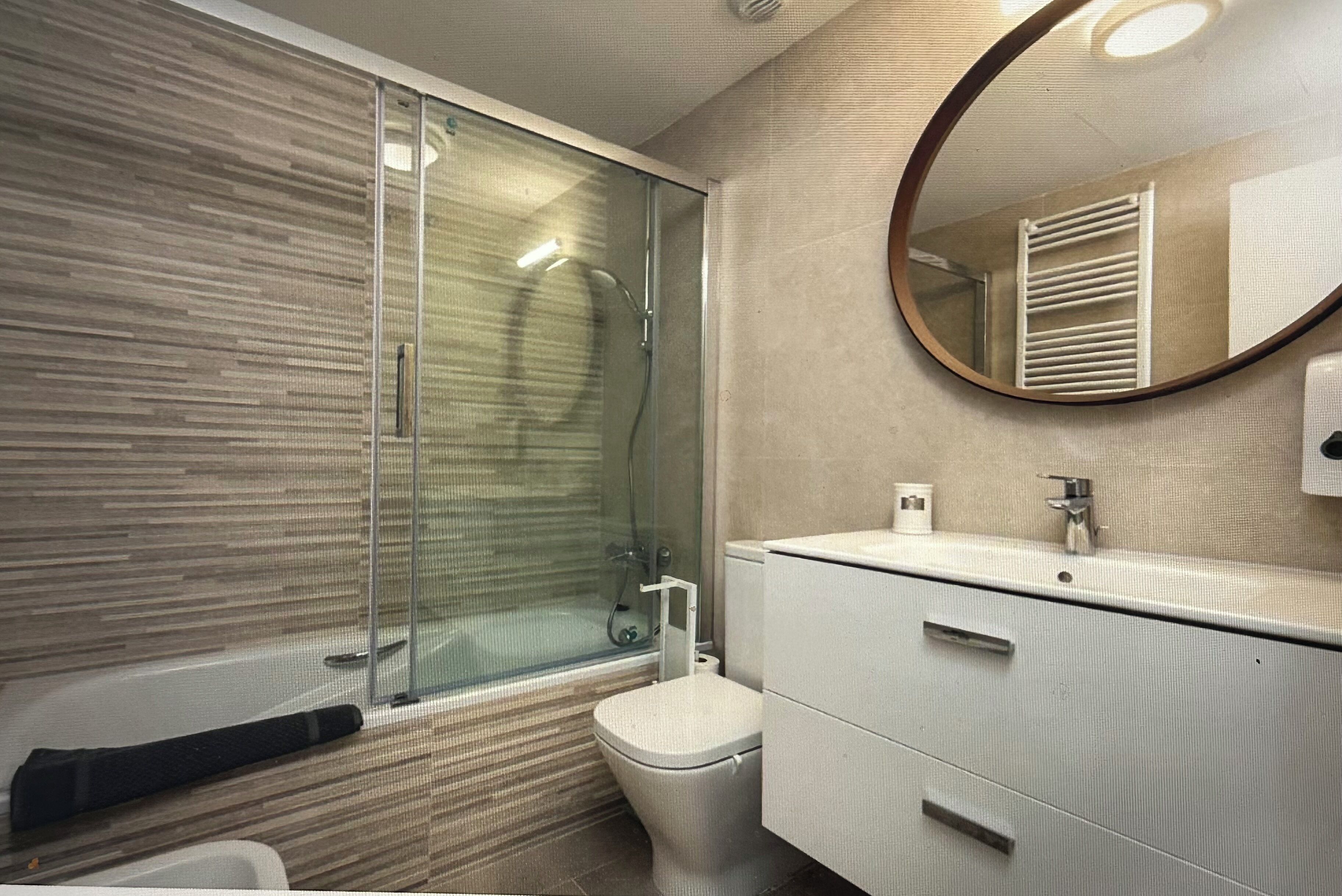 A modern bathroom with a glass-enclosed shower, a toilet, and a vanity with drawers.