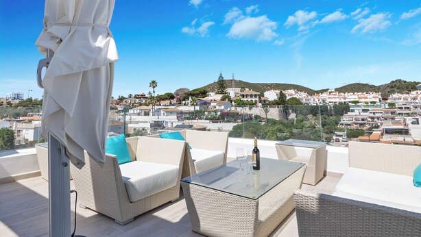 A terrace with wicker furniture, a glass table, and a view of a coastal town. - WHITE HOUSE : Charming & spacious Villa, Big terrace with sea & mountain views . (Fuengirola)