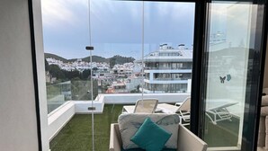 A balcony with a view of a cityscape, a wicker sofa with cushions, and a glass door. - WHITE HOUSE : Charming & spacious Villa, Big terrace with sea & mountain views . (Fuengirola)