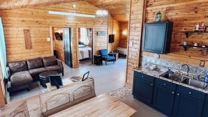 A wooden cabin interior with a living area, kitchen, and dining space. -  Cabin on private beach on a lake near Brainerd! 2 bedrooms, sleeps 7! (Brainerd)