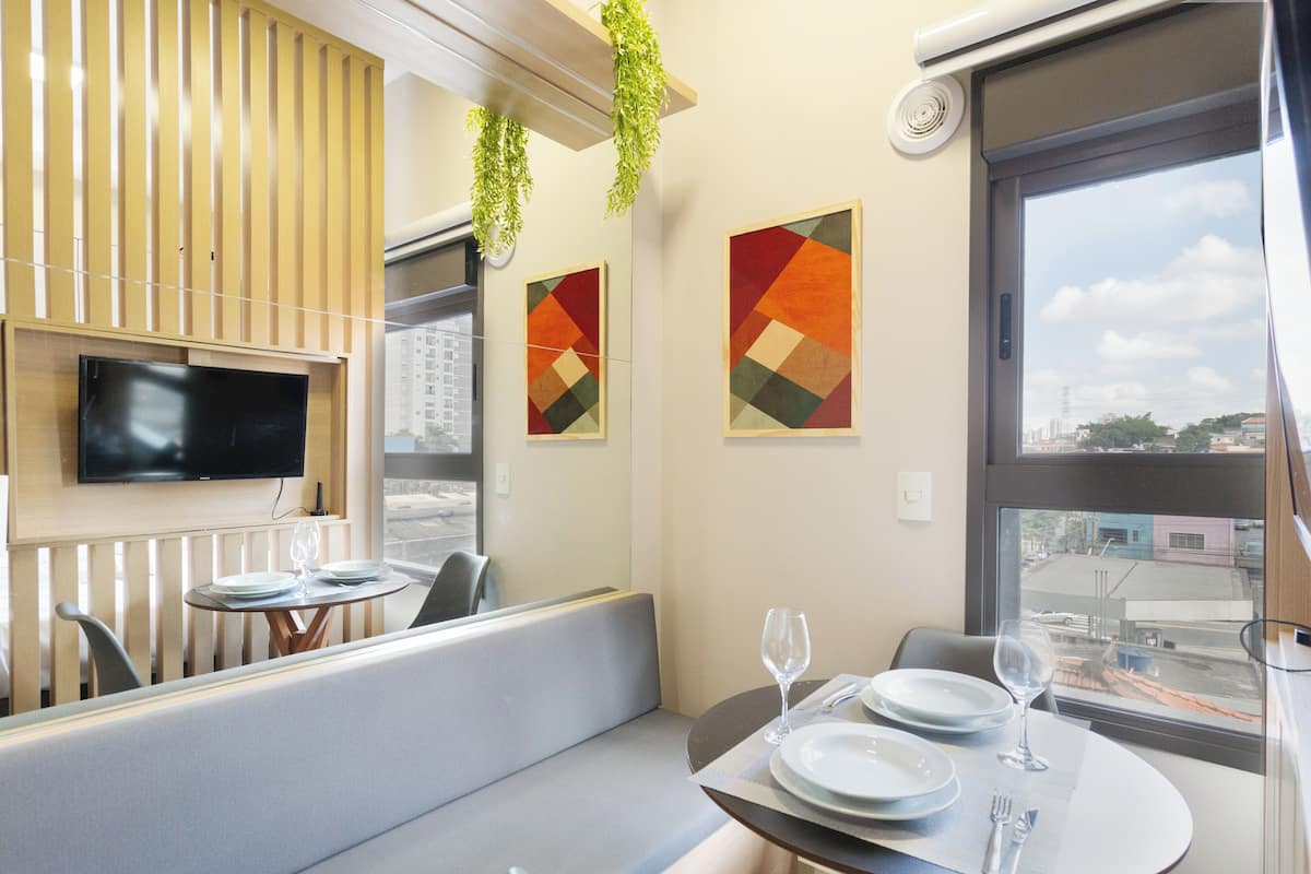 Un espace repas moderne, doté d’un téléviseur, de deux tables et d’œuvres d’art accrochées aux murs.