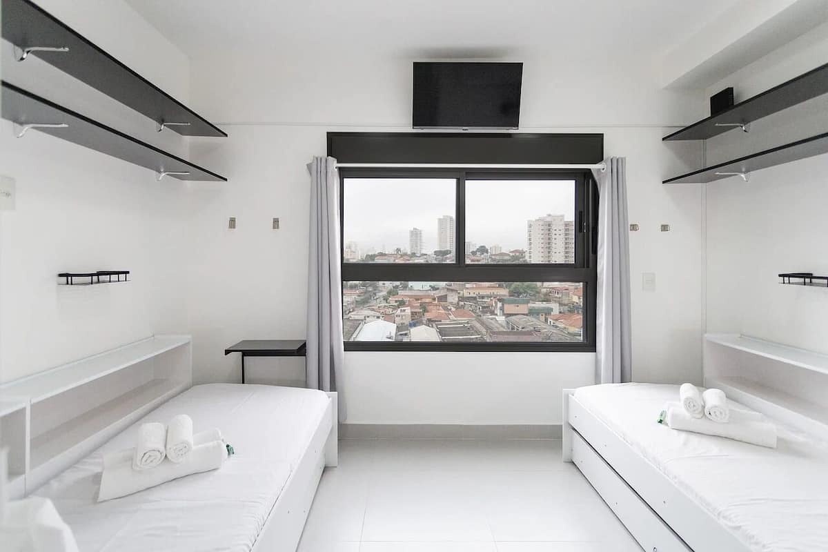 Une chambre d’hôtel moderne avec deux lits, une télévision et une vue sur la ville.