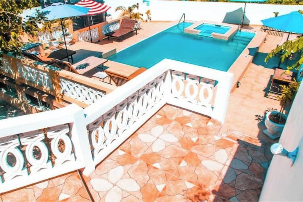 A rooftop pool area with a clear blue pool, lounge chairs, and umbrellas.