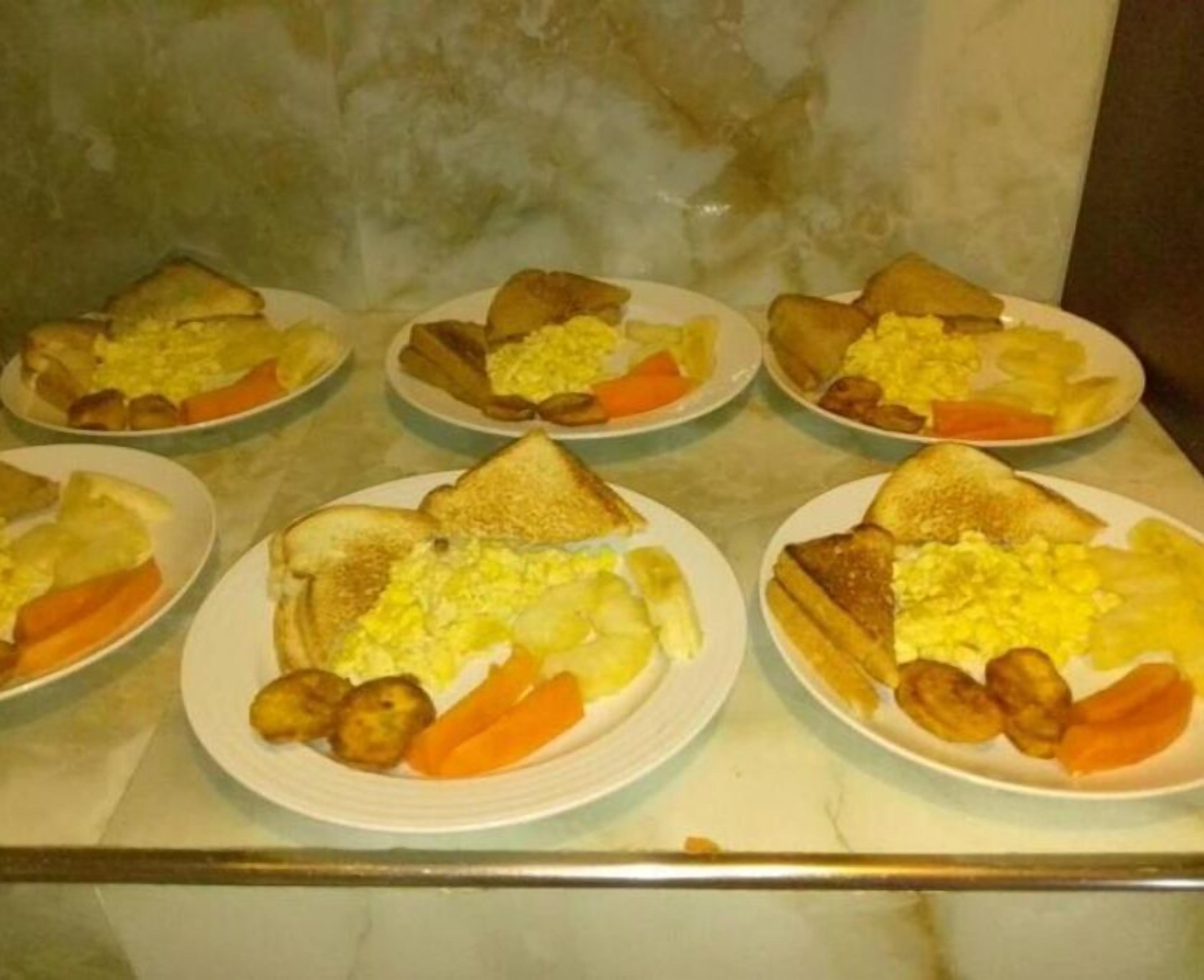A breakfast buffet with plates of toast, scrambled eggs, potatoes, and carrots.