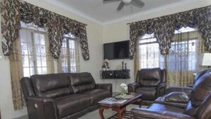 A living room with a sofa, armchairs, a coffee table, and a TV.