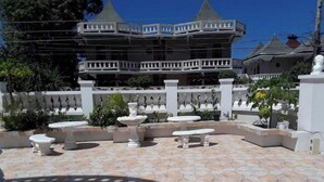 A courtyard with stone flooring, white benches, and a fountain.