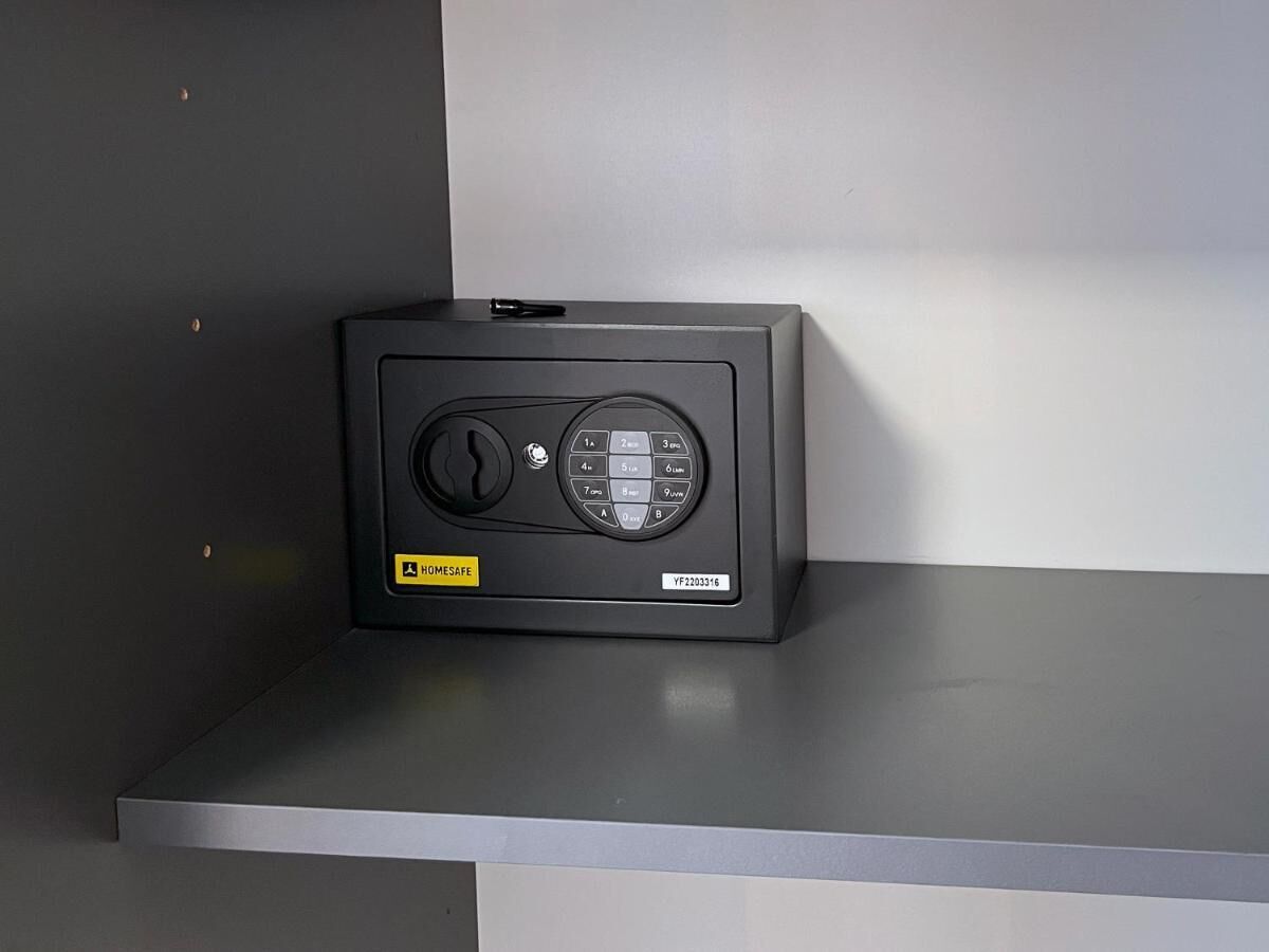 Una caja fuerte negra con cerradura y dial, sobre una superficie gris.