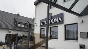 A hotel named "HOTEL DONA" with a modern facade, large windows, and a visible staircase leading to the entrance. - Haven - Hotel Dona (Bergisch Gladbach)