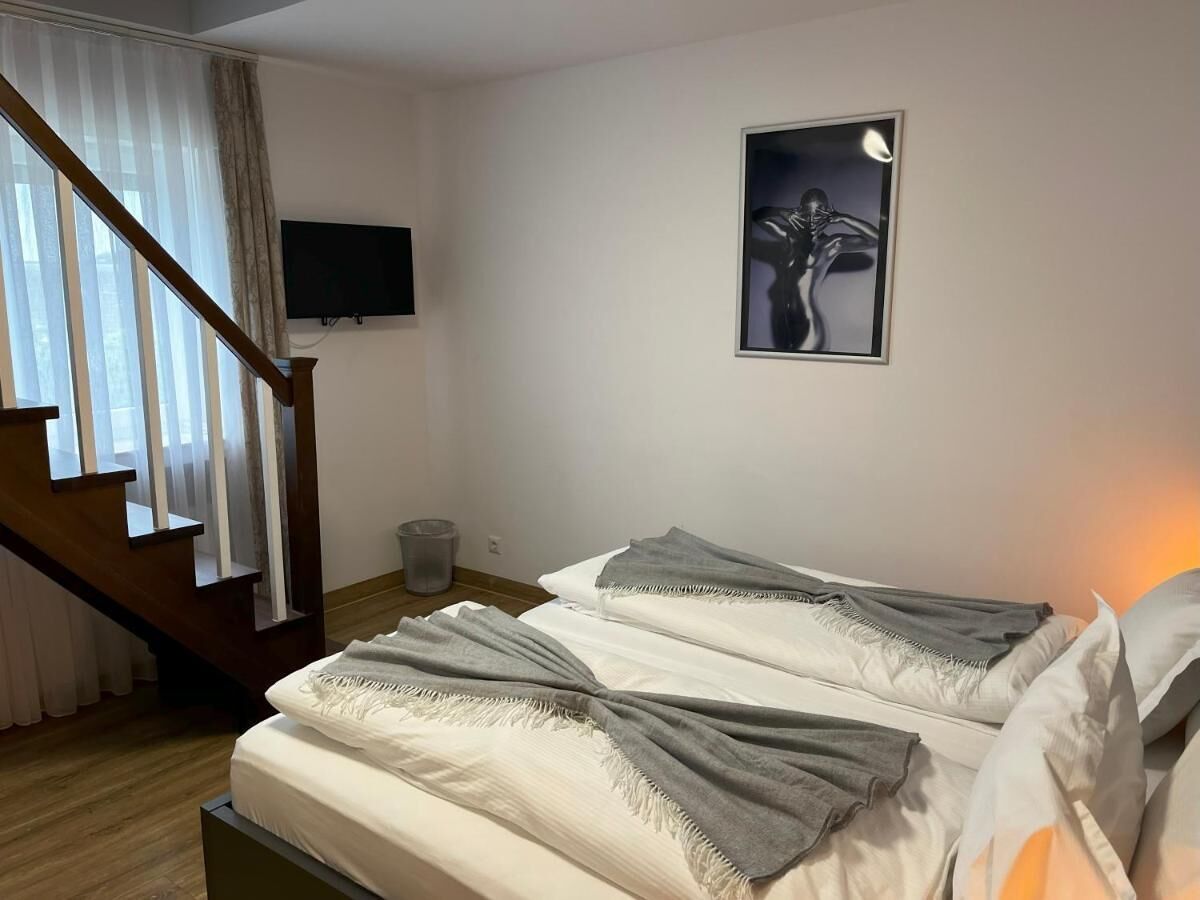 A bedroom with a bed, a TV, a staircase, and a framed picture on the wall.