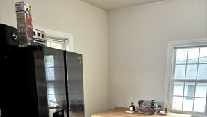 A compact kitchen with a black refrigerator, wooden table, and a small bench.