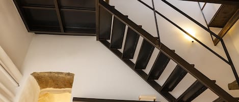 Un escalier moderne avec une structure en métal noir et un mur blanc.