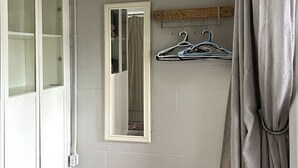 A room with a white door, a mirror, and a wooden coat rack with hangers. - Waterfront coastal cottage charm in delightful Port Royal (Port Royal)