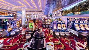 Un casino con numerosas máquinas tragamonedas, taburetes de bar y suelo alfombrado.