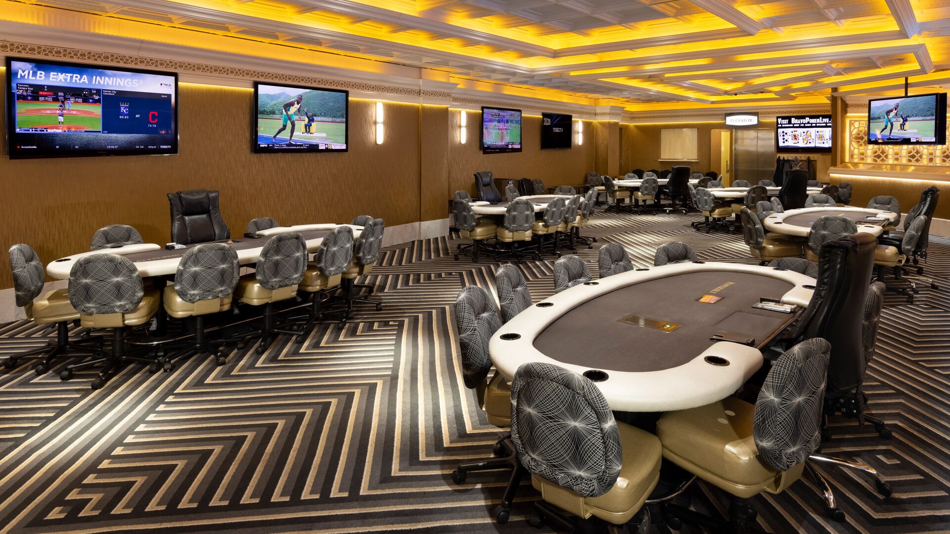 A conference room with multiple tables and chairs, equipped with large screens displaying sports events.
