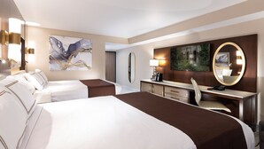 Habitación de hotel con dos camas, un escritorio, una silla, un espejo grande y obras de arte en las paredes.