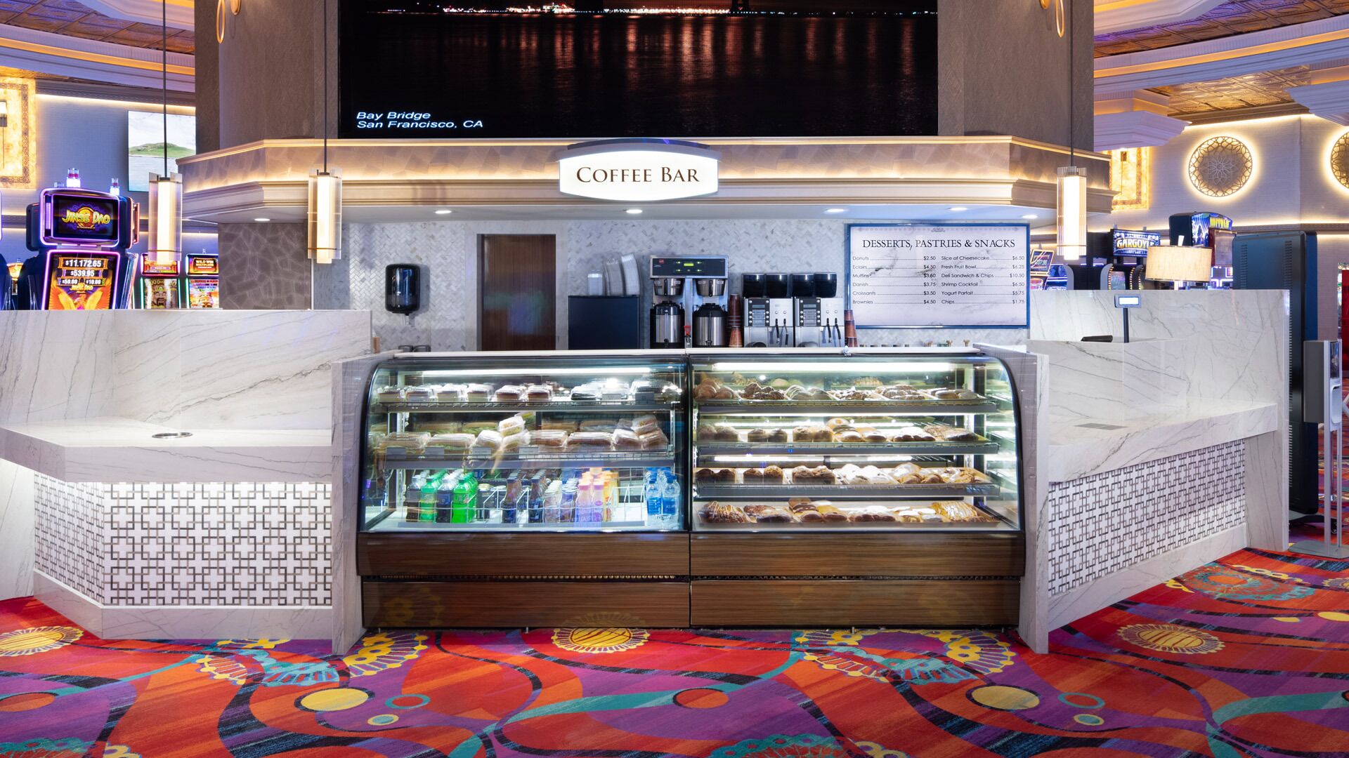 A coffee bar with a menu board, a cash register, and a display case with pastries.