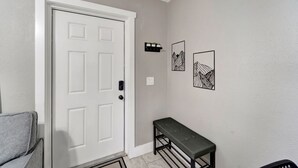 A hallway with a white door, a bench, and two framed pictures on the wall.