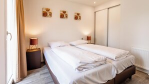 A double bed with white linens, two bedside tables with lamps, a sliding door closet, and three wall-mounted basketball-themed artworks. - Holiday Home With gas Fireplace & Bath (Bemelen)