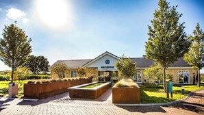 A reception area with a clear sign, paved walkway, and landscaped garden with trees and planters. - Holiday Home With gas Fireplace & Bath (Bemelen)