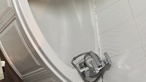 Una bañera con cabezal de ducha y un rociador de mano.