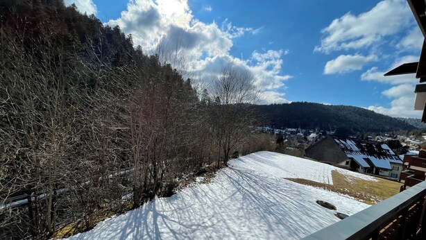 A snow-covered landscape with a view of a village and mountains in the background.