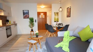 A compact living space with a kitchenette, a dining area, and a sofa with pillows.