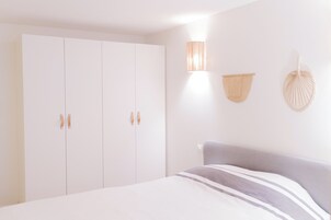 A bedroom with a bed, a wardrobe, and wall-mounted lamps.