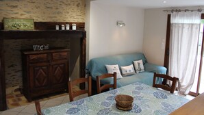 Une pièce chaleureuse avec un meuble en bois, un canapé bleu et une table recouverte d’une nappe à motifs.