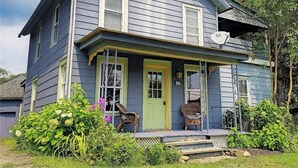 A two-story house with a porch, a star decoration above the entrance, and two wicker chairs on the porch.
