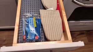 Een keukulaag met een marmeren aanrechtblad, met daarin een pak afwasmiddel, een doek en een houten lepel.