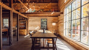Un comedor amplio con una larga mesa de madera y sillas, rodeado de ventanas grandes y paredes de madera.