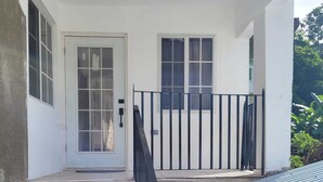 A white building with a metal staircase leading to a door, a metal railing, and a metal roof.