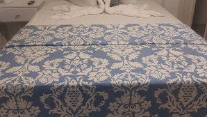 A neatly made bed with a blue and white patterned bedspread, a white pillow, and a gray pillow.