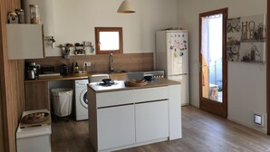 Eine kleine Küche mit Waschmaschine, Kühlschrank und einer Holz Arbeitsplatte.